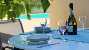 Una mesa redonda con una botella de vino, dos copas de vino y un plato.
