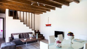 Una sala de estar moderna con una escalera, un comedor y un televisor.