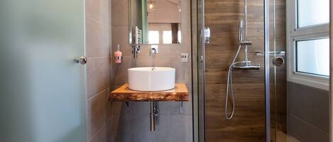 A modern bathroom with a glass-enclosed shower, a wooden vanity, and a large mirror.