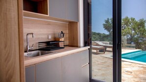 A modern kitchen with a built-in sink, wooden cabinets, and a view of a swimming pool.
