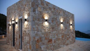 A stone building with exterior lighting, a door, and a view of the sea.