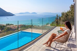 A balcony with a glass barrier overlooking a swimming pool and a view of the sea and distant mountains. - Special Offer - Villa With Private Pool (Lefkada)