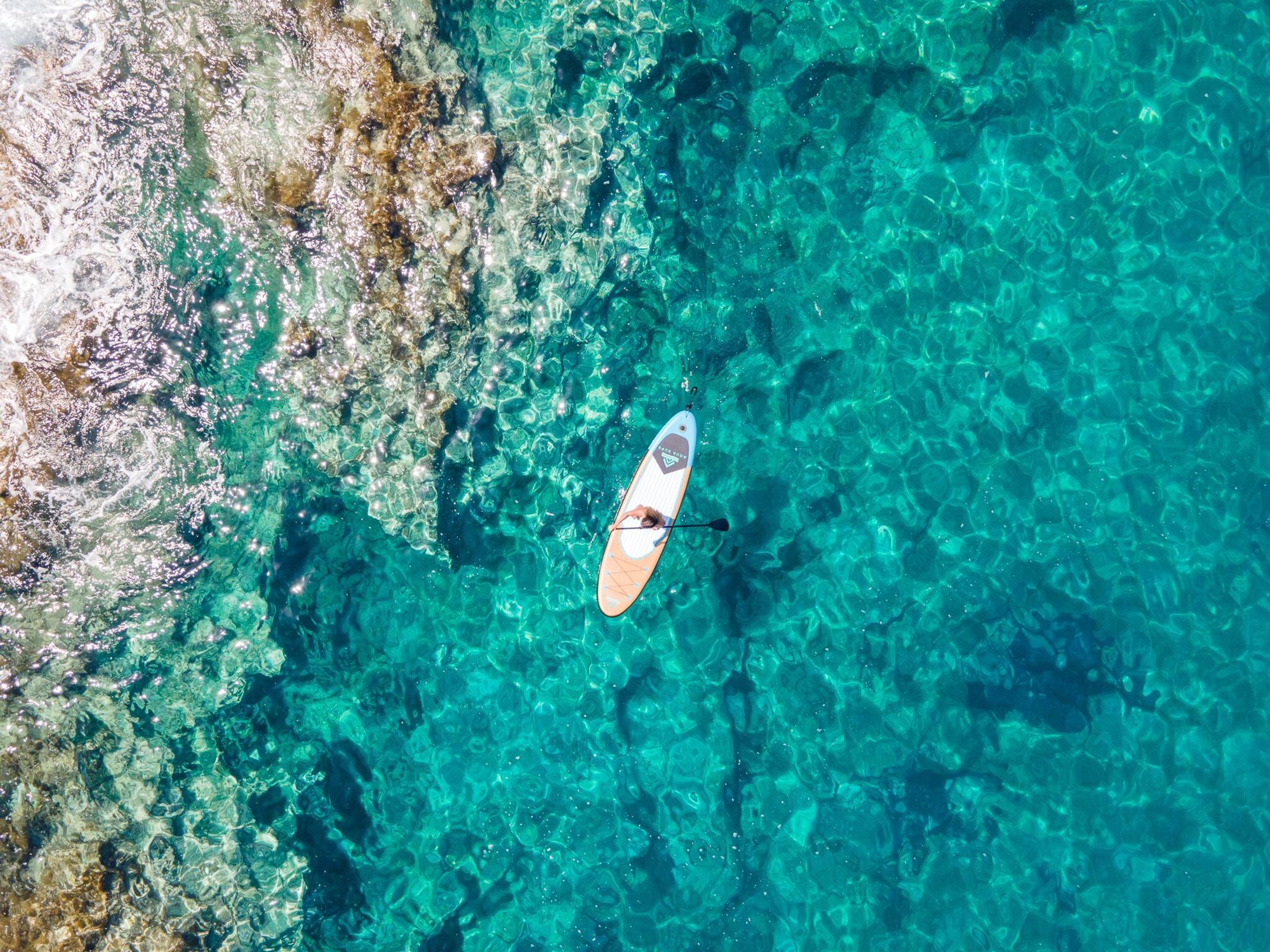 A clear aerial view of a beach with a paddleboard.