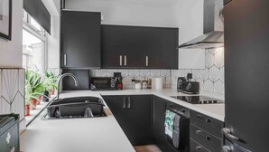 A modern kitchen with black cabinets, a white countertop, and a built-in oven. - 3 Mins to Stadium W M Dishwasher Sofa Bed (Liverpool)