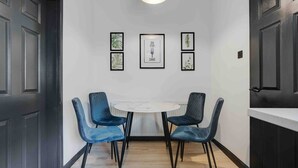 A dining area with a round table, four blue chairs, and framed botanical prints on the wall. - 3 Mins to Stadium W M Dishwasher Sofa Bed (Liverpool)