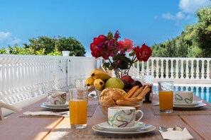 A breakfast table with fruits, pastries, and beverages, overlooking a pool. - Dream 2 BED in Ponti (Lefkada)