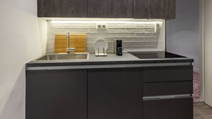 Uma cozinha moderna com armários escuros, uma pia de aço inoxidável e uma cafeteira embutida.