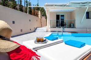 A poolside area with lounge chairs, a table with drinks, and a view of the pool. - Villa Alba in Lefkada (Lefkada)