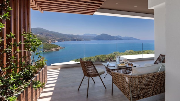 A balcony with wicker furniture, a table with a plate and a glass, and a view of the sea and mountains. - Zavia Villa DYO 3B Syvota (Igoumenitsa)