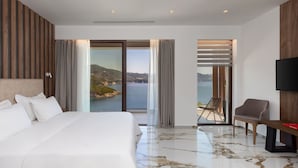 A hotel room with a bed, a chair, a TV, and a view of the sea. - Zavia Villa DYO 3B Syvota (Igoumenitsa)
