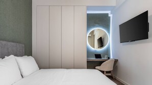A modern hotel room with a large bed, a desk with a chair, a flat-screen TV, and a circular mirror. - Beehive Ground in Athens (Athens)