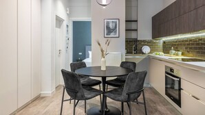 A modern kitchen with a round dining table, black chairs, and a pendant light. - Beehive Ground in Athens (Athens)