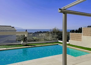 Une piscine avec vue sur la mer et les collines.