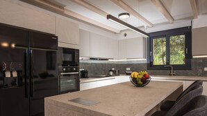 Uma cozinha moderna com uma ilha grande, eletrodomésticos de aço inoxidável e uma janela com vista para o verde.