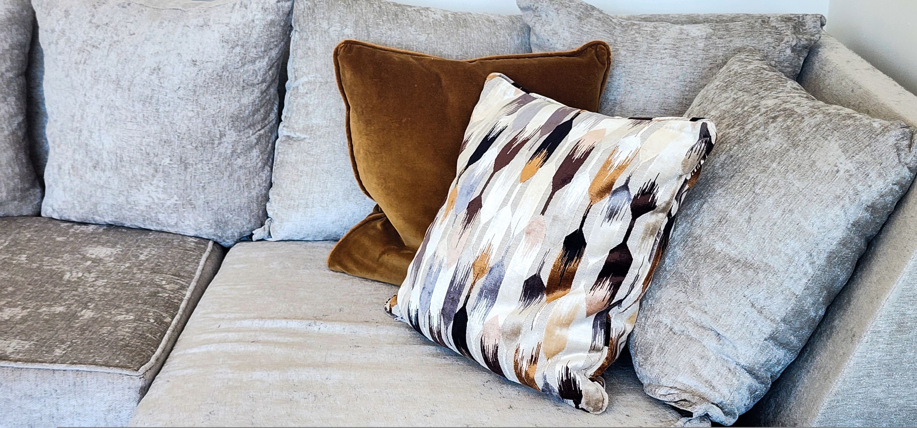 A sectional sofa with a patterned throw pillow and a solid brown accent pillow.