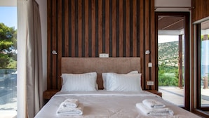 Une chambre avec un grand lit, un mur lambrissé en bois et une vue sur la verdure.
