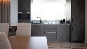 Une cuisine moderne avec des meubles de couleur sombre, un évier en acier inoxydable et une fenêtre au-dessus du plan de travail.