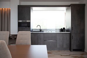 A modern kitchen with dark cabinetry, a stainless steel sink, and a window above the countertop. - Zavia Penthouse 2B Syvota (Igoumenitsa)