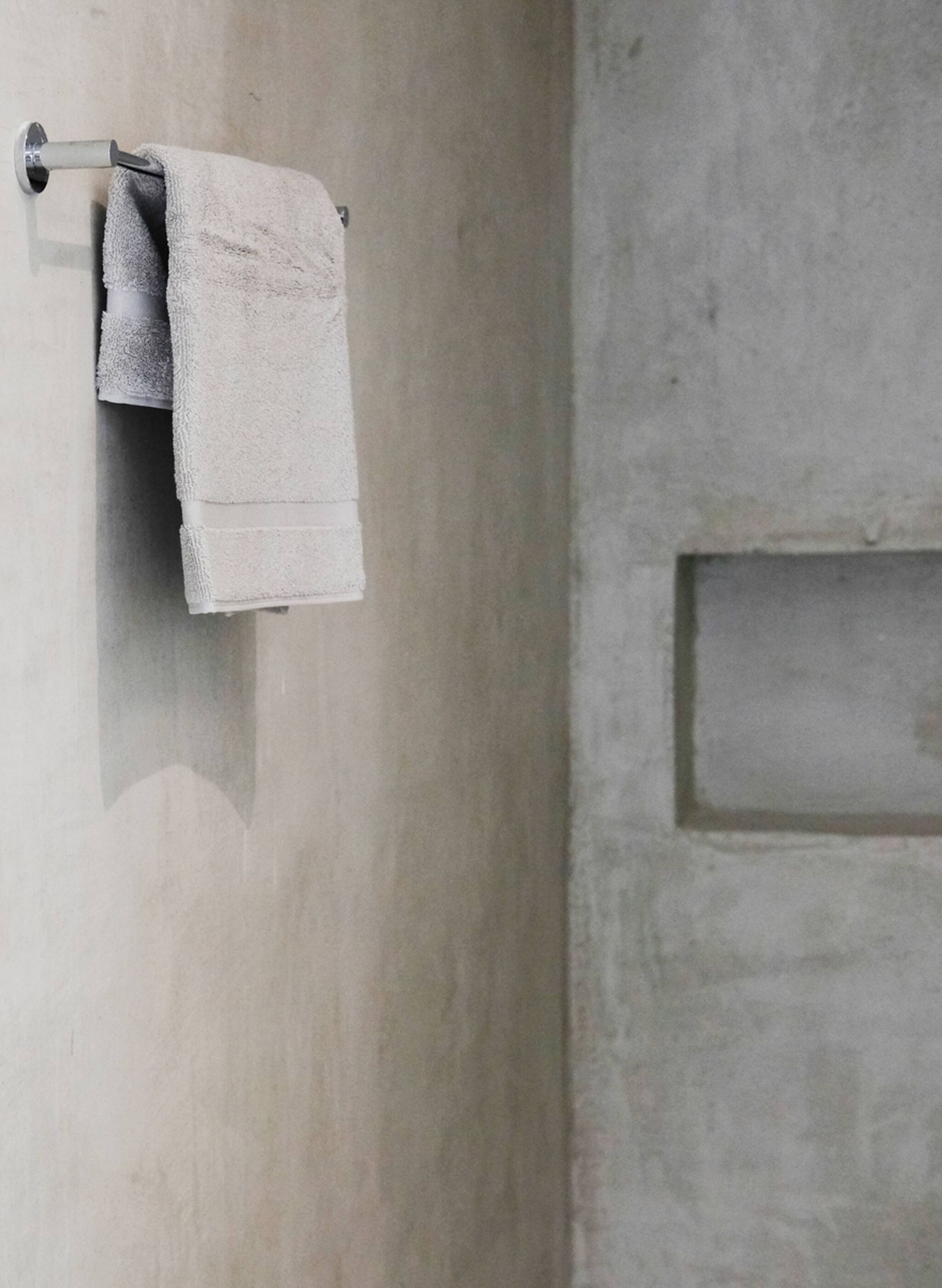 A bathroom with a towel hanging on a metal towel rack against a textured wall.