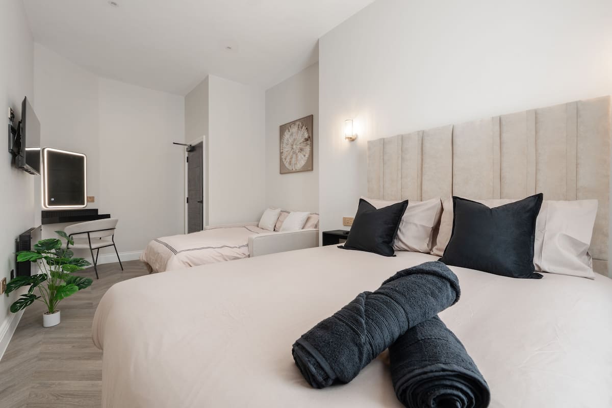 Habitación de hotel con cama, escritorio, silla, televisor y planta en maceta.