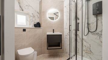 Un baño moderno con inodoro, lavamanos y ducha.