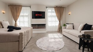 Uma sala de estar moderna com lareira, sofá, cama e televisão na parede.