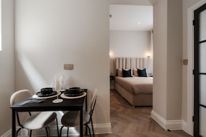 A dining area with a table, chairs, and a bed in the background. - Bold St Aparthotel Book Individually or Book 8! (Liverpool)