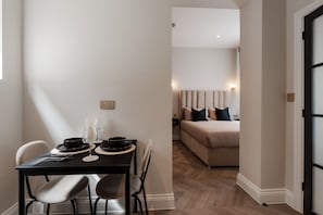 Un comedor con una mesa, sillas y una cama al fondo.