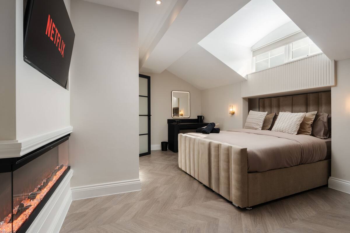 Un dormitorio con cama, televisor montado en la pared, escritorio y espejo.