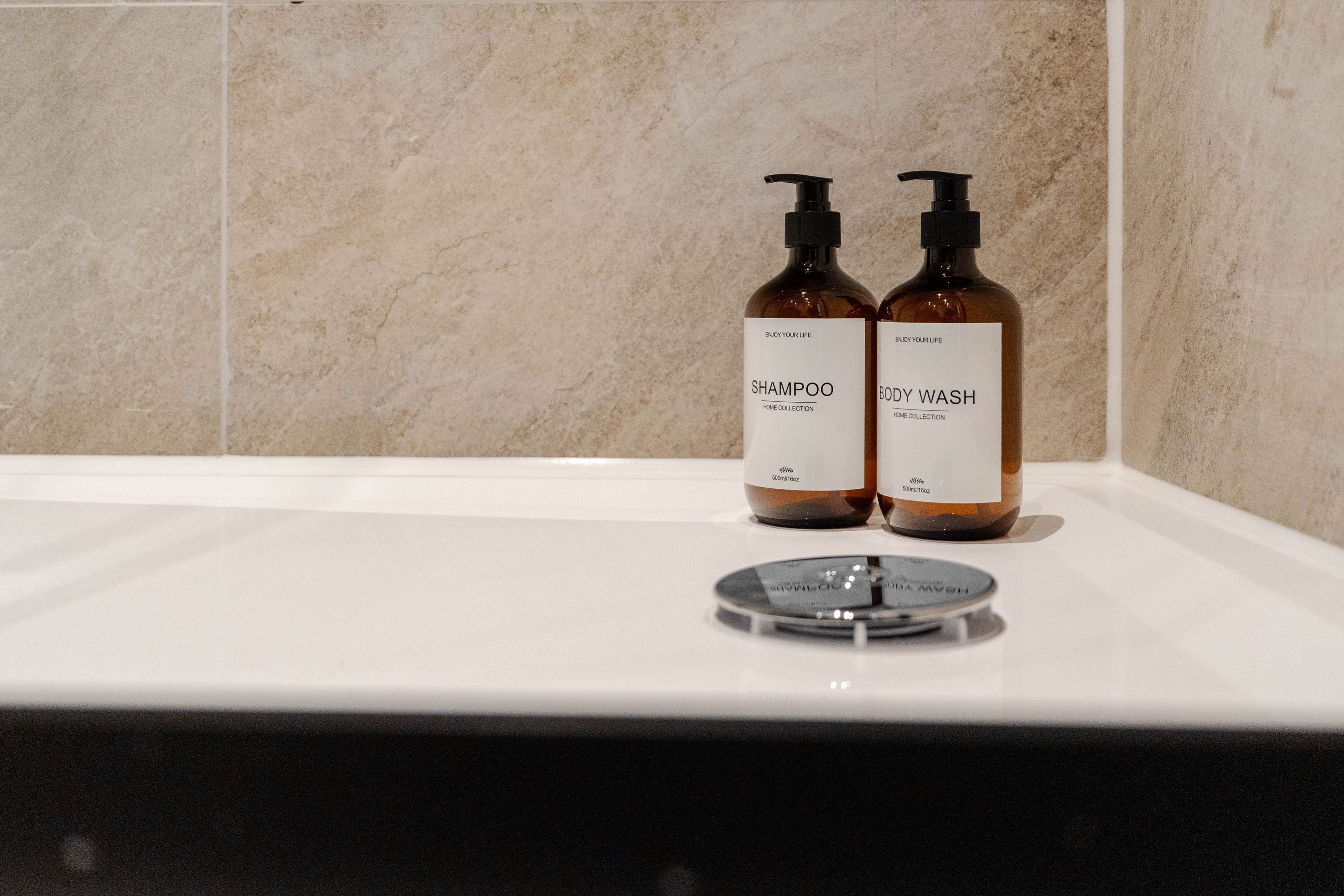 Dos botellas de jabón corporal y champú sobre una encimera de baño.