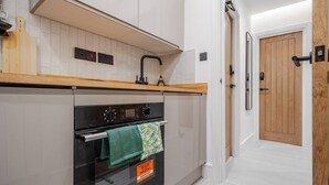 A modern kitchen with white cabinets, a wooden countertop, a black oven, and a wooden door. - Work Desk Private Ensuite Minifridge Parking (Liverpool)