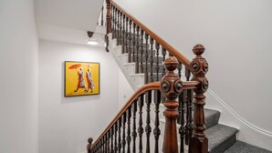 A staircase with a wooden handrail and black balusters, carpeted steps, and a framed artwork on the wall. - Work Desk Private Ensuite Minifridge Parking (Liverpool)