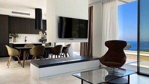 A modern living space with a kitchen, dining area, and a large TV. - Scirocco Penelope 2 BED (Lefkada)