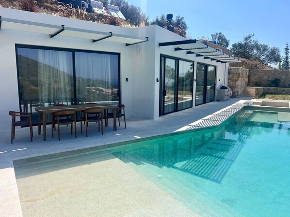 Una casa moderna con piscina, puertas correderas de vidrio y un comedor.