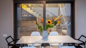 Un comedor con una mesa, sillas y un jarrón con flores.