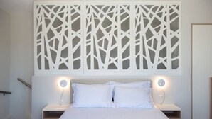 Un dormitorio con cama, mesitas de noche y un panel decorativo en la pared.