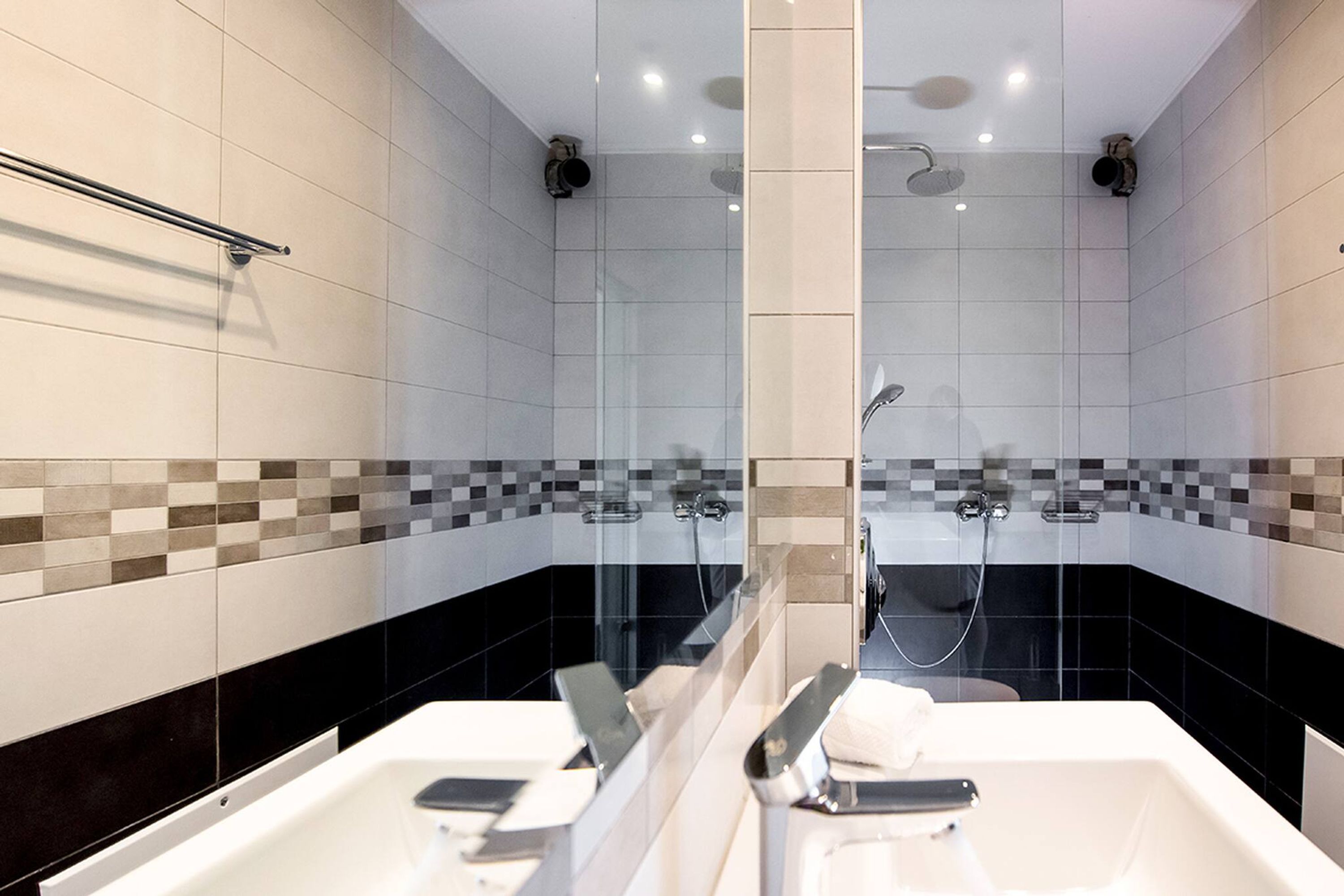 Une salle de bain moderne avec une paroi en verre, un espace douche et un lavabo avec un porte-serviette.