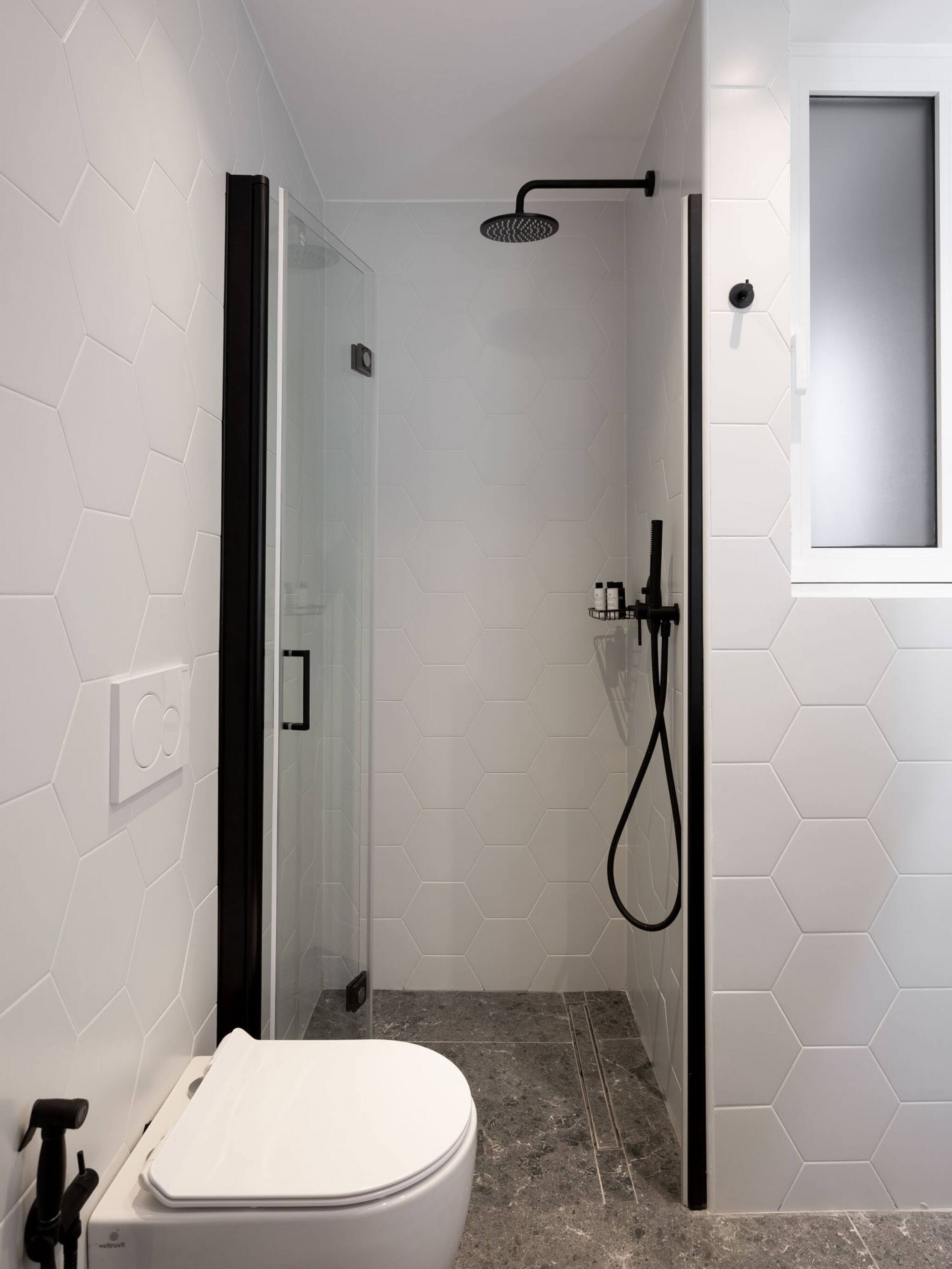 Une salle de bain moderne avec une douche, des toilettes et une petite fenêtre.