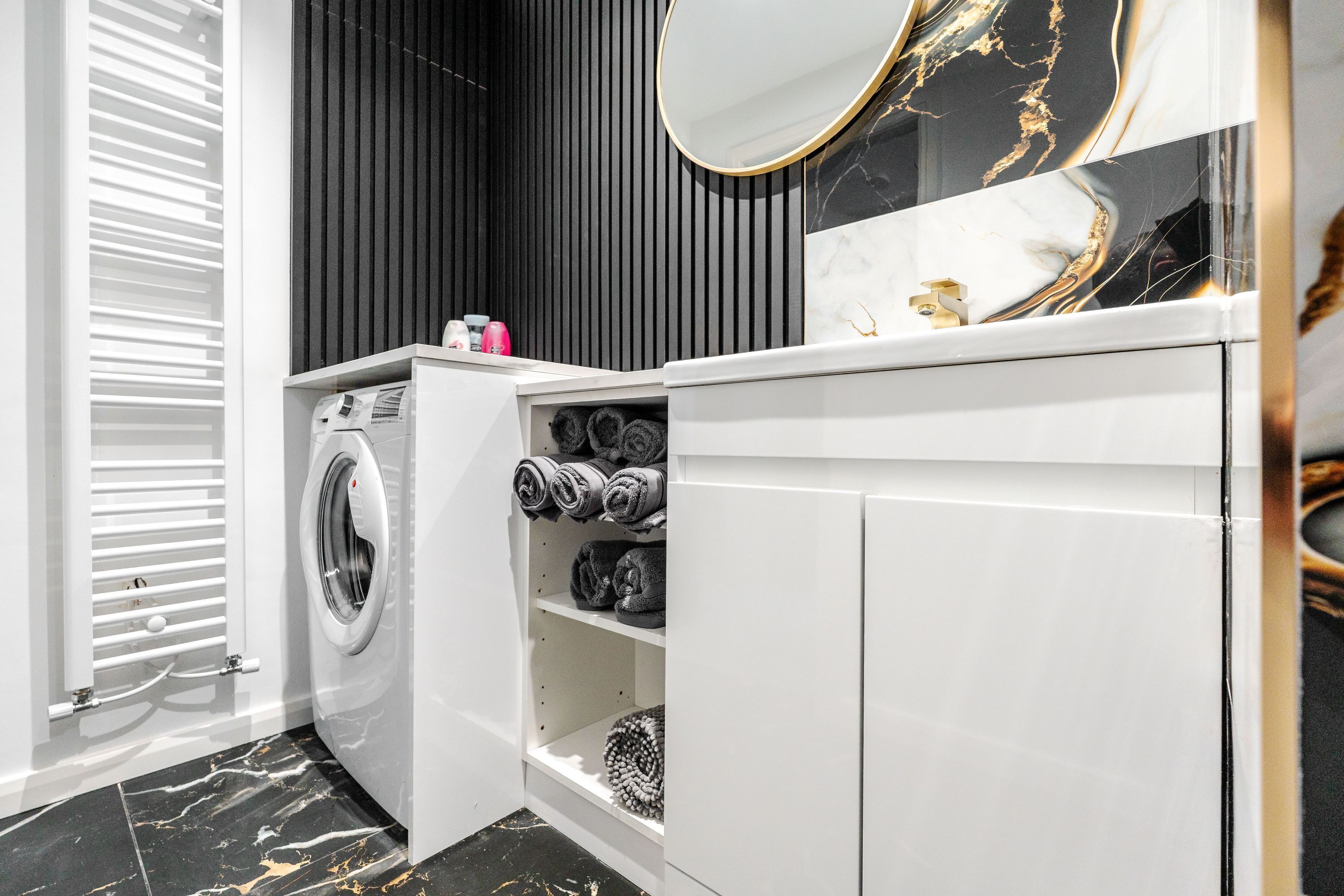 Une salle de bain moderne équipée d’un lave-linge intégré, d’un miroir et de serviettes rangées avec soin.