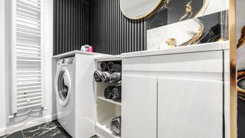 Une salle de bain moderne équipée d’un lave-linge intégré, d’un miroir et de serviettes rangées avec soin.