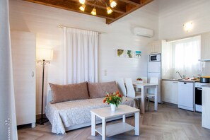 A compact living space with a sofa, a dining table, a kitchen area with a microwave and refrigerator, and a small decorative plant on the table. - Vissala2 Paeonia in Vasiliki (Lefkada)