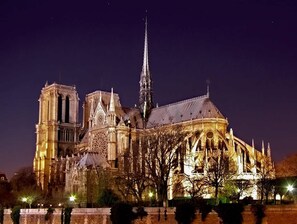 A historic cathedral with a prominent spire, detailed Gothic architecture, and illuminated by artificial lighting. - Historic Parisian Gem Chic Central Retreat (Paris)