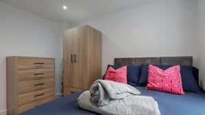 Ein Schlafzimmer mit einem Bett, einem Holzschrank und einem Kopfteil mit Kissen.