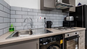 A modern kitchen with a stainless steel sink, a coffee maker, a microwave, and a dishwasher. - Smart TV W M With Sofa Bed Free Parking (Liverpool)