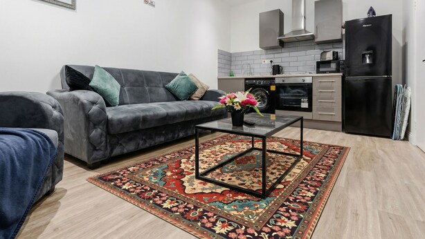 A modern living room with a grey sofa, a glass coffee table, and a patterned rug. - Smart TV W M With Sofa Bed Free Parking (Liverpool)