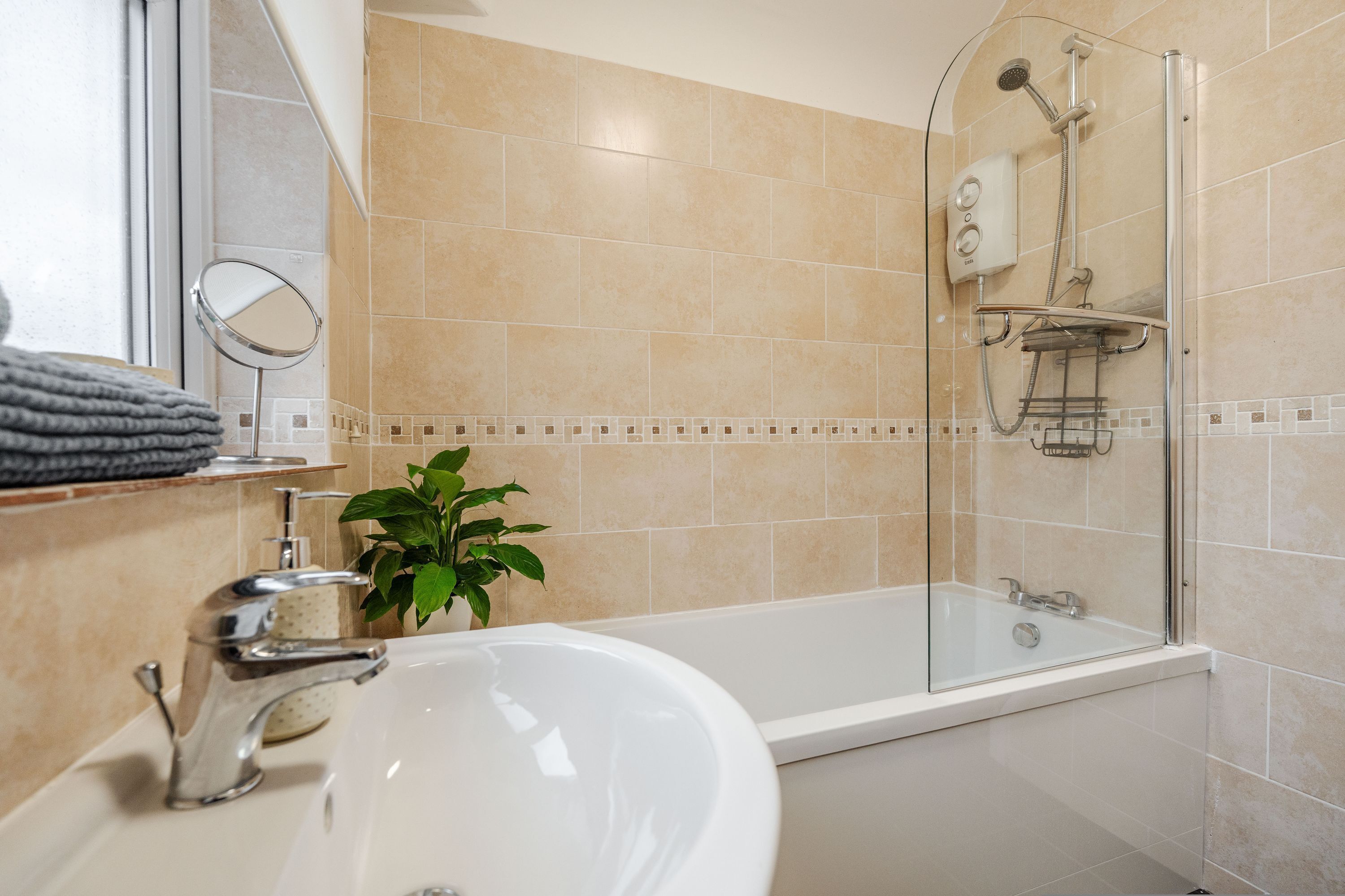 A bathroom with a bathtub, a shower, a sink, and a mirror.