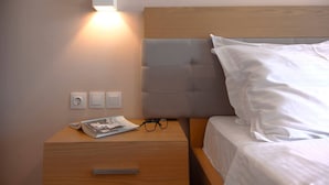 A neatly made bed with white linens, a bedside table with a magazine and glasses, and a wall-mounted light fixture. - Villa Alkistis in Lefkada (Lefkada)