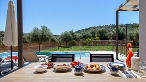 A dining table with breakfast items, a pool, and a view of the countryside. - Villa Alkistis in Lefkada (Lefkada)