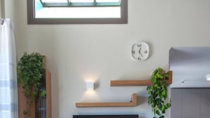 A modern living room with a flat-screen TV, wooden shelves, a clock, and a plant. - Villa Alkistis in Lefkada (Lefkada)
