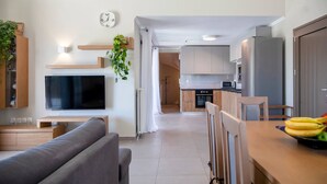 A modern kitchen with a flat-screen TV, wooden cabinets, and a dining area with a table and chairs. - Villa Alkistis in Lefkada (Lefkada)